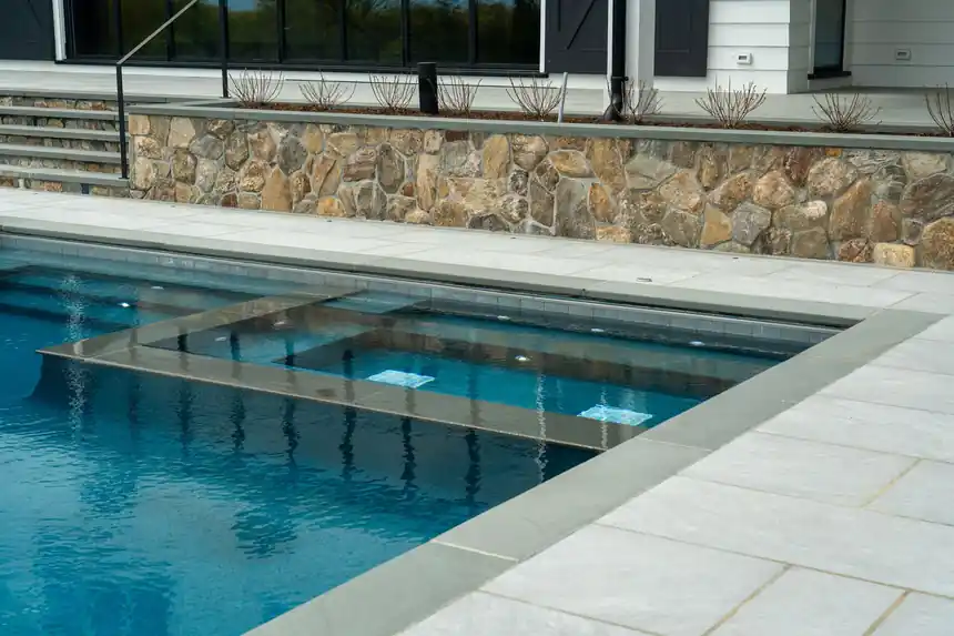 Spa shelf and underwater lights against a stone wall at a Greenwich pool
