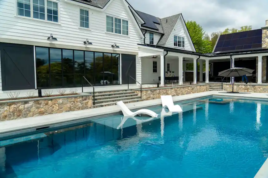 In-water lounge chairs on a tanning ledge in front of a white house