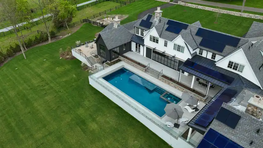 Oblique aerial view of a glass-edge pool beside a modern house