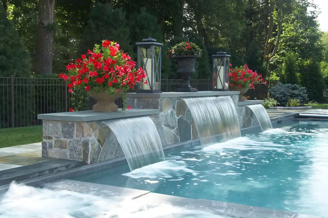 Three sheer descents falling from a stone wall into a pool