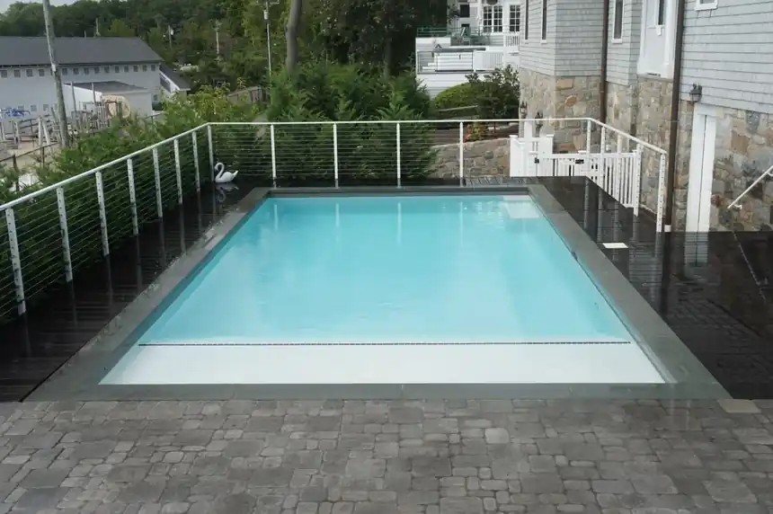 Raised pool with a cable railing over a dark deck