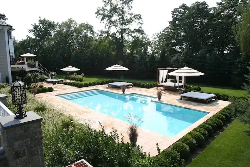 Pool with lounge daybeds set among trimmed hedges