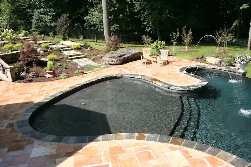 Dark-finish lagoon pool with rock, flagstone and fountain jets